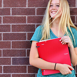 girl smiling holding binder notes school wall red green smile blonde hair hands portrait natural