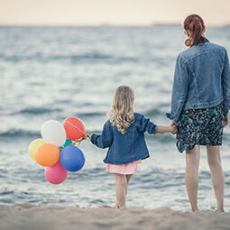 mum daughter beach balloons looking at the sea holding hands summer poland Baltic travel UGC content
